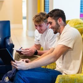 3 guys sitting in yellow chairs smiling with notepads