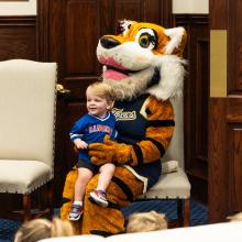 Young male boy sitting with tiger mascott 