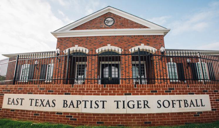 The ETBU Tiger Softball Clubhouse brick building front with a blue in the background.