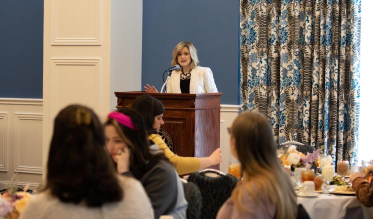 Woman behind a podium speaking to a room of women
