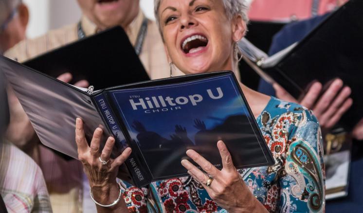 Woman singing with a hilltop choir book in her hands