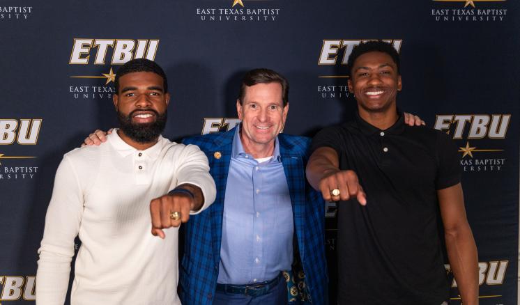 Two seniors show off their rings with ETBU President Dr. Blair Blackburn at the Ring Blessing Spring 2024 ceremony