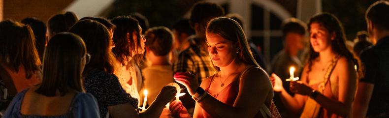 Female students lighting candles at event at night