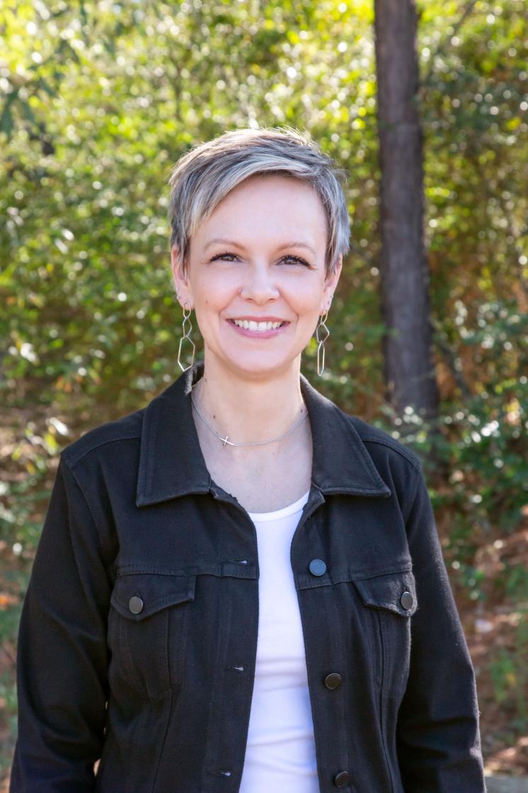 A woman smiling at the camera outside.