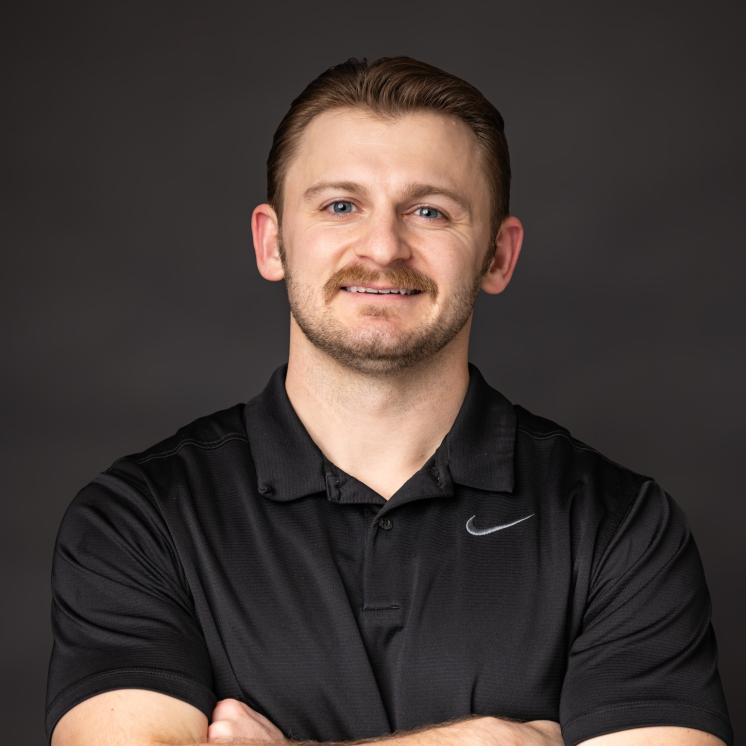 A man in a black nike shirt standing infront of a dark backdrop