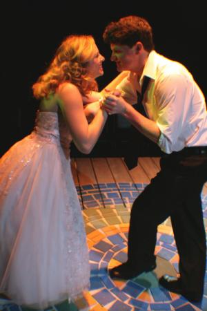 A man and a woman in formal clothing dancing on a stage