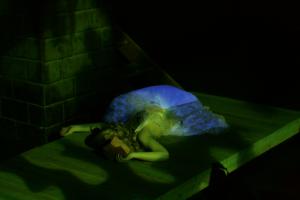 A woman laying flat on a wooden pallet, pretending to be dead for a theatre play
