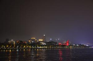 Nighttime city skyline with colorful illuminated buildings and reflections on the water.