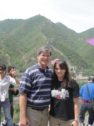 Two people standing in front of green mountains.