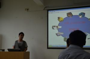 a teacher standing at the head of a class the students are looking at a projector