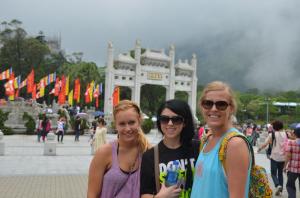 3 people outside with a large chinese gate behind them