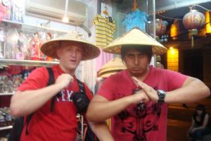 Two people wearing straw hats posing in a souvenir shop.