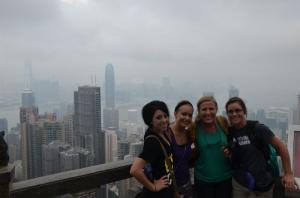 a photo of a city skyline looking down in the fog with people posing on the balcony
