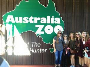 A group of people stands in front of the Australia Zoo sign featuring a map of Australia.