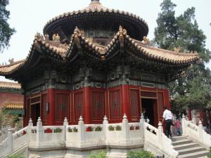 Traditional Chinese pavilion with red walls and a tiered, ornate roof.
