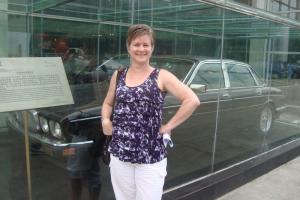 Woman standing in front of a glass case containing a vintage black car.
