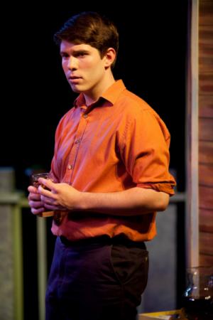 A man standing under dimly lit lighting in business casual clothes looking afar
