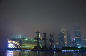 Nighttime city skyline with colorful illuminated buildings and reflections on the water.