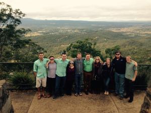 A group of ten people standing at a scenic overlook with a valley and mountains in the background.