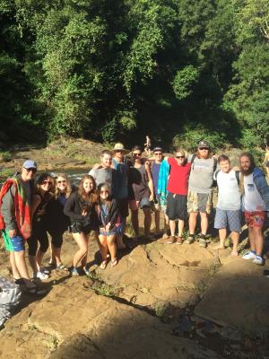 A group of people posing on rocks by a river, surrounded by dense greenery.