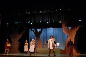 A group of people standing together on a stage with a prop background under spotlighting in old clothes