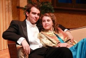 Two people in formal attire seated on a sofa.