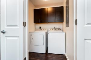 Compact laundry room with a dryer, washing machine, and overhead dark wooden cabinet.