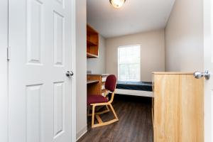 Small dorm room with a desk, chair, bed, and window.