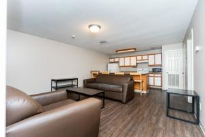 A modern living room with wooden flooring, brown leather furniture, a dark coffee table, and a light wooden dining set.