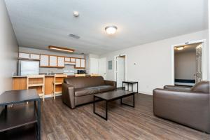 A modern living room with wooden flooring, brown leather furniture, a dark coffee table, and a light wooden dining set.