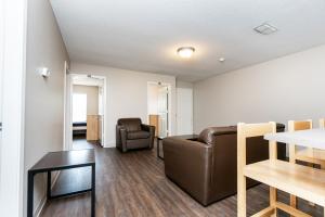 A modern living room with wooden flooring, brown leather furniture, a dark coffee table, and a light wooden dining set.