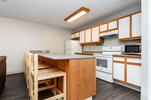 Modern kitchen with white cabinets, stove, microwave, and refrigerator.