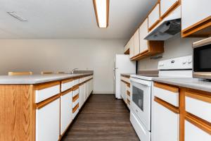 Modern kitchen with white cabinets, stove, microwave, and refrigerator.