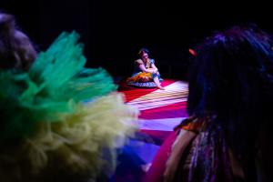 Woman sitting on ground alone during theatre performance of Cagebirds