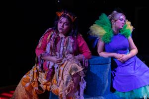 Two women sitting and staring off camera during theatre performance of Cagebirds 