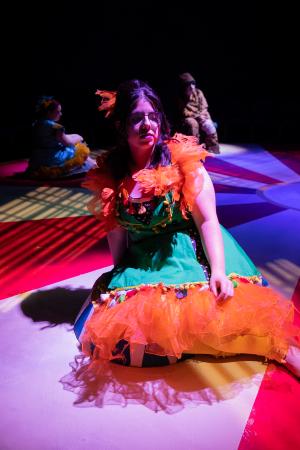 Woman sitting in foreground while two other women sit in background during Cagebirds Theatre Production   