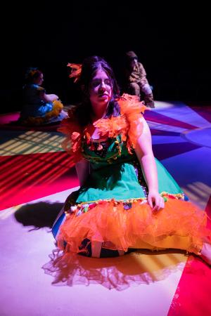 Woman sitting in foreground while two other women sit in background during Cagebirds Theatre Production   