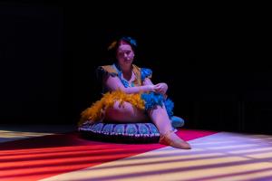 Woman sitting alone on the ground during Cagebirds Theatre Production 