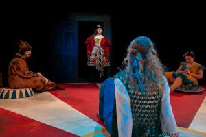 Woman walking through door in front of three sitting women during Cagebirds Theatre Production 