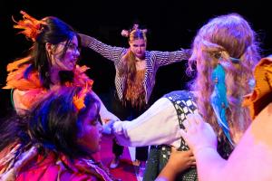 Women in foreground with woman posing in background during Cagebirds Theatre Production