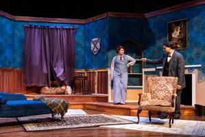 A stage set of an elegant living room with two people in conversation.