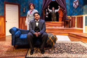 A scene from a stage play depicting a vintage living room with characters in period costumes.
