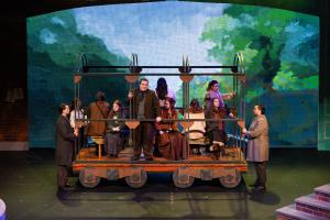 A group of people on a stage standing inside a trolley