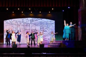 A group of people expressing emotion on a stage with dim lighting
