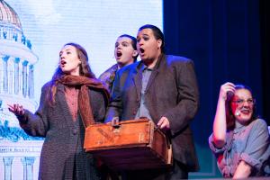 A group of people with shocked expressions on a stage under bright lighting