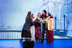 A group of people stood together talking on a stage with expression
