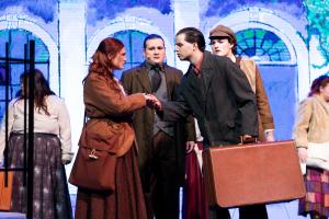 A man stood talking to a woman on a stage with a briefcase