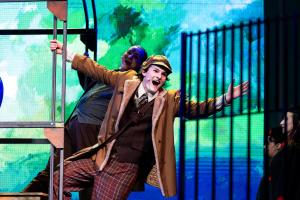 A man hanging out of a trolley on a stage during a play