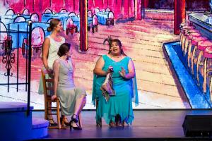 2 women sat talking to eachother on a stage during a play