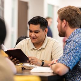 Male students studying at a table with books open